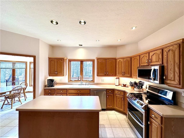 kitchen featuring stainless steel appliances, a sink, light countertops, and brown cabinets