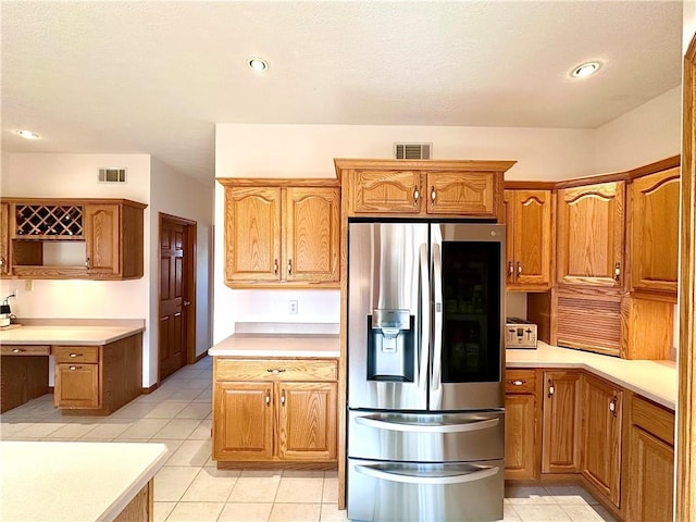 kitchen featuring built in desk, stainless steel fridge, visible vents, and brown cabinets