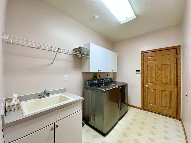 laundry room with cabinet space, baseboards, washer and dryer, light floors, and a sink