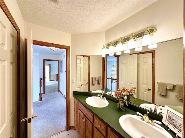 full bathroom featuring a textured ceiling, double vanity, and a sink