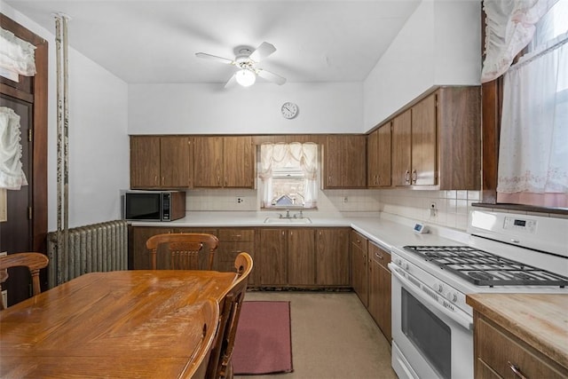 kitchen with black microwave, ceiling fan, light countertops, decorative backsplash, and white gas range