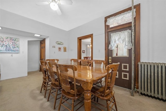 dining space featuring light carpet, radiator heating unit, and a ceiling fan