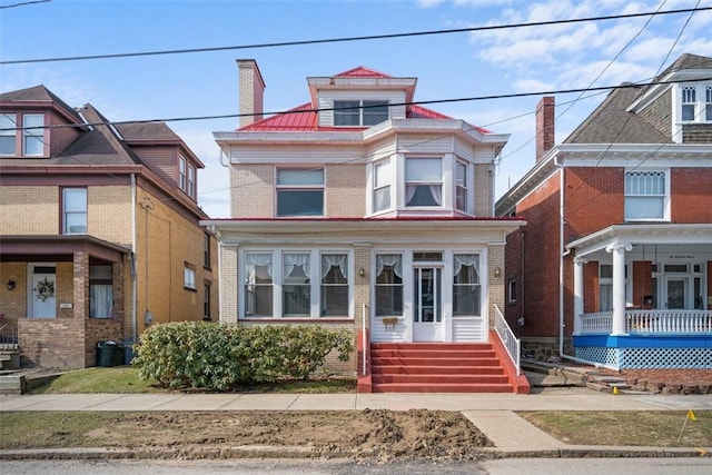 view of front of house featuring a chimney and brick siding