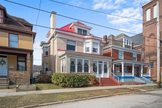 view of front of property with entry steps, a chimney, and brick siding