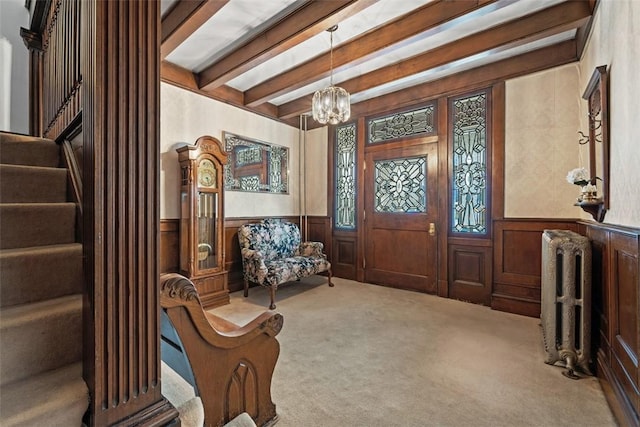 carpeted entrance foyer featuring wainscoting, beamed ceiling, stairway, and radiator heating unit