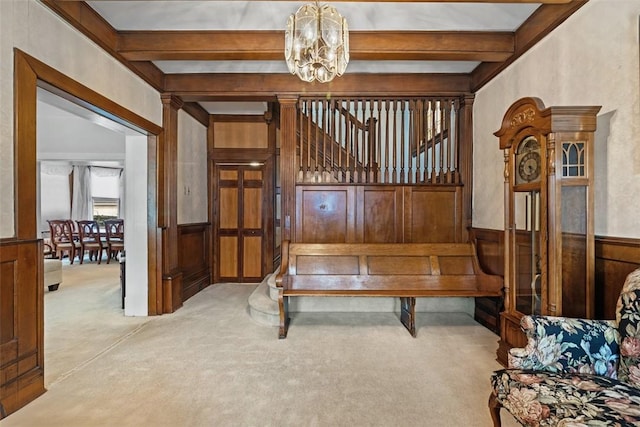 sitting room featuring a chandelier, carpet flooring, beamed ceiling, and wainscoting