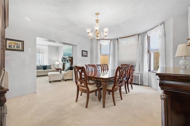 dining room featuring a chandelier, light carpet, and radiator heating unit