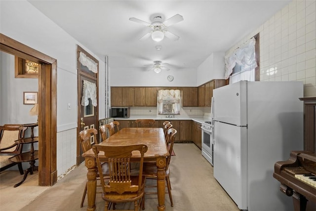 kitchen featuring ceiling fan, white appliances, a sink, light countertops, and brown cabinetry