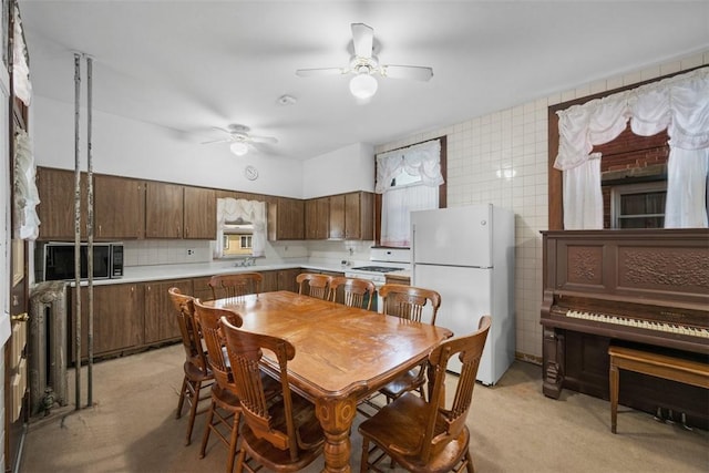 dining space featuring a ceiling fan and tile walls