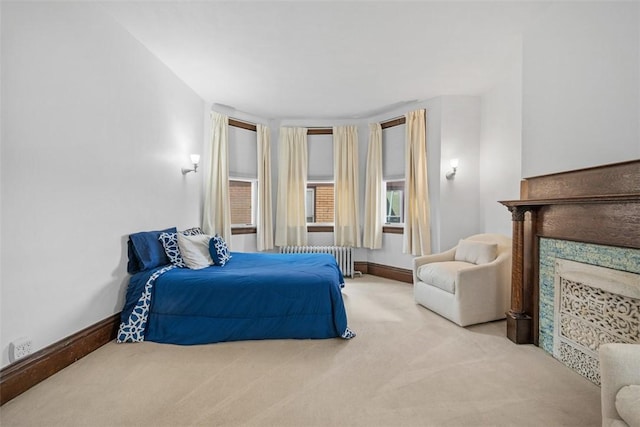 carpeted bedroom with radiator, a fireplace, and baseboards