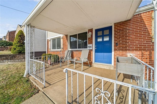 doorway to property featuring a porch and brick siding