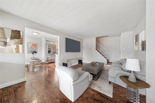 living area featuring hardwood / wood-style floors, stairway, and baseboards