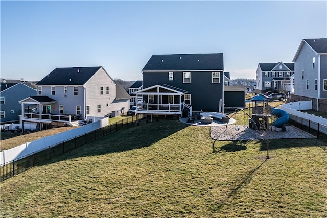 back of house with a yard, an outdoor fire pit, a fenced backyard, and a residential view