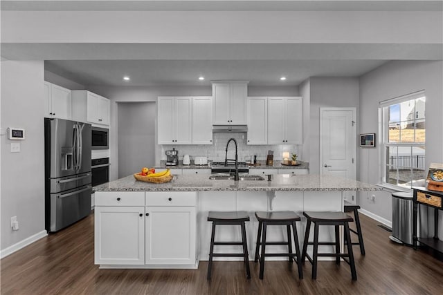 kitchen with tasteful backsplash, oven, built in microwave, stainless steel refrigerator with ice dispenser, and a sink