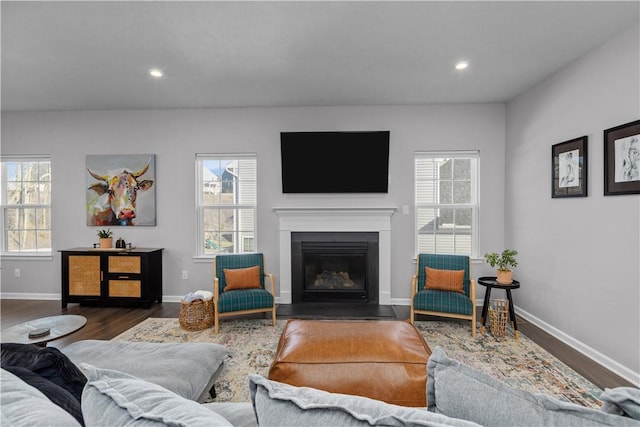 living area featuring a glass covered fireplace, dark wood-style flooring, a healthy amount of sunlight, and recessed lighting