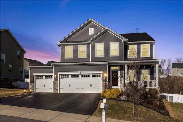 traditional-style house with aphalt driveway, stone siding, a porch, and an attached garage