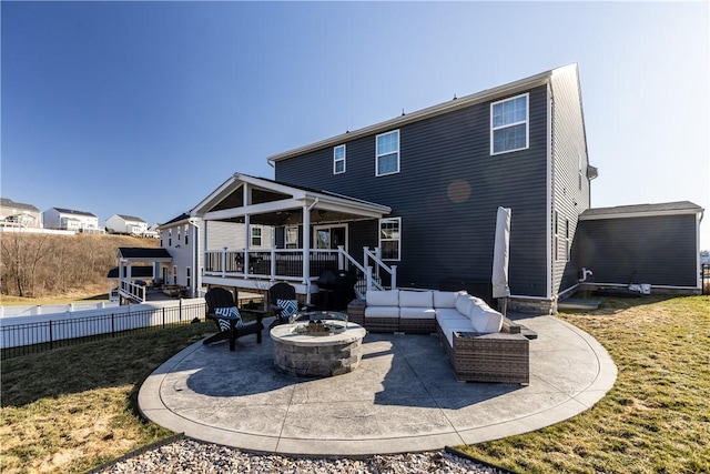 rear view of property with a patio, a yard, fence, and an outdoor living space with a fire pit