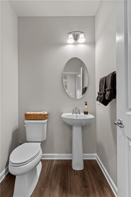 bathroom with a sink, toilet, baseboards, and wood finished floors