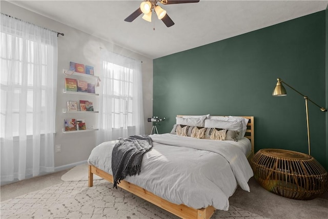 carpeted bedroom with ceiling fan, multiple windows, and baseboards