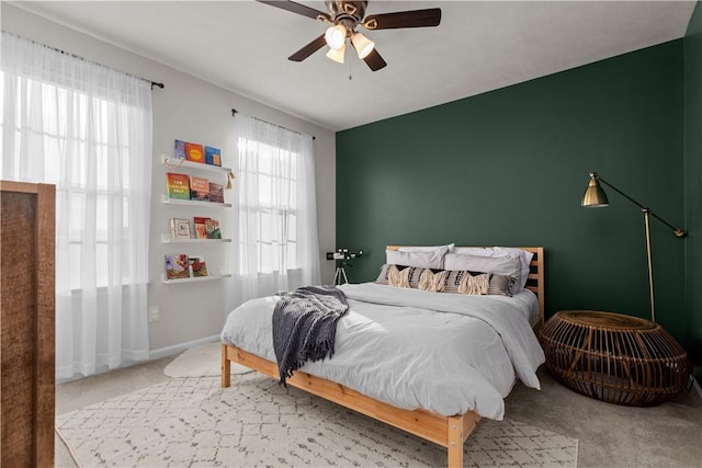 bedroom featuring carpet floors, multiple windows, baseboards, and a ceiling fan