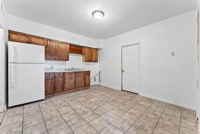 kitchen with baseboards, light countertops, a sink, and freestanding refrigerator