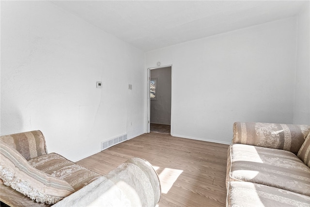 living room featuring visible vents, baseboards, and wood finished floors