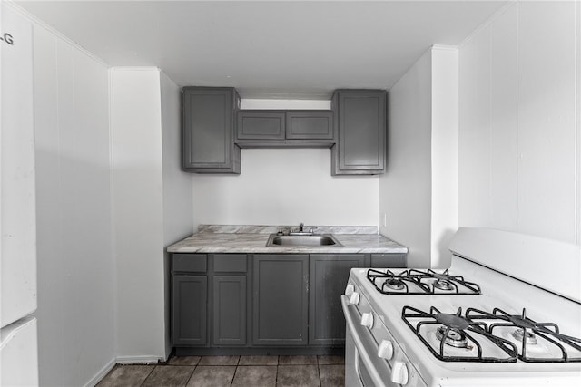 kitchen featuring a sink, light countertops, gas range gas stove, and gray cabinets