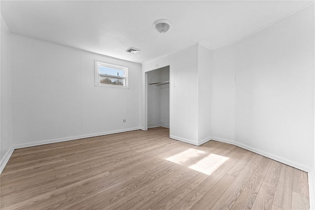 unfurnished bedroom with a closet, wood finished floors, visible vents, and baseboards