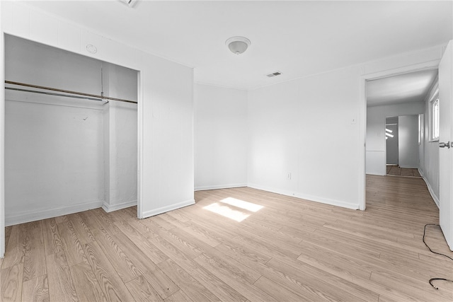 unfurnished bedroom featuring light wood-type flooring, a closet, visible vents, and baseboards