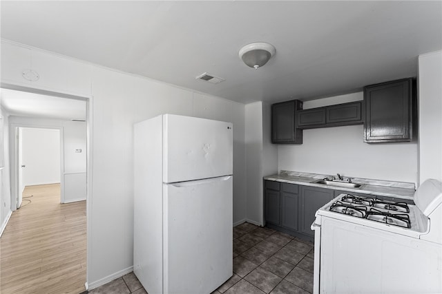 kitchen with gray cabinetry, white appliances, a sink, visible vents, and light countertops