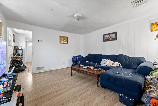 living area with visible vents, wood finished floors, and ornamental molding