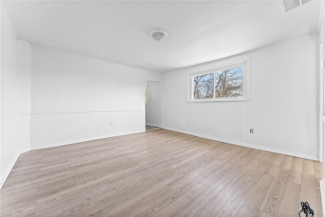 spare room featuring wood finished floors, visible vents, and baseboards