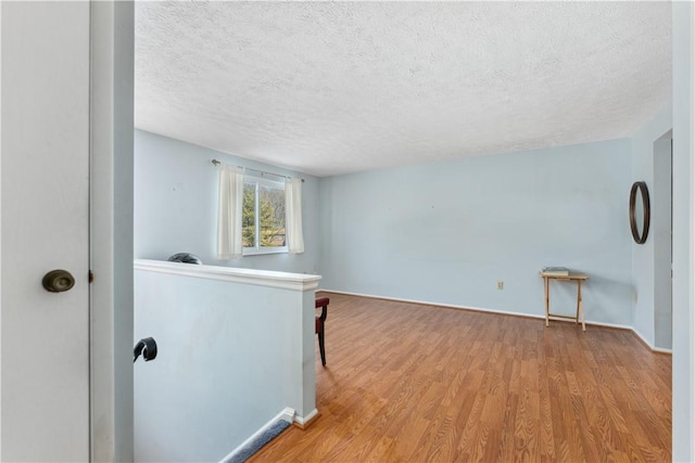 unfurnished room with a textured ceiling and wood finished floors