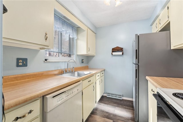 kitchen featuring dark wood finished floors, light countertops, visible vents, white dishwasher, and a sink