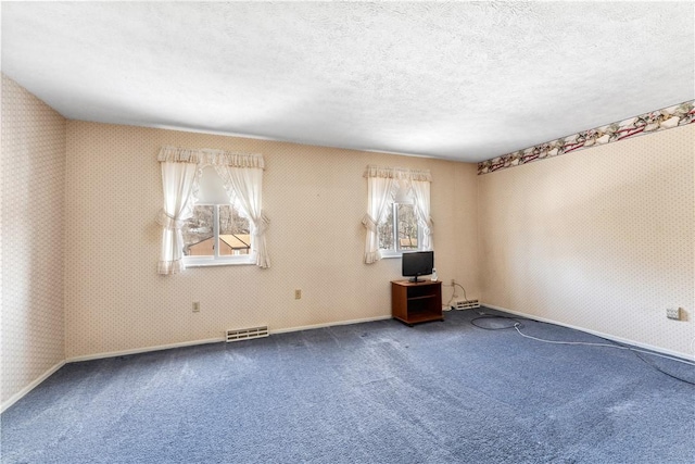 carpeted spare room with wallpapered walls, visible vents, a wealth of natural light, and a textured ceiling