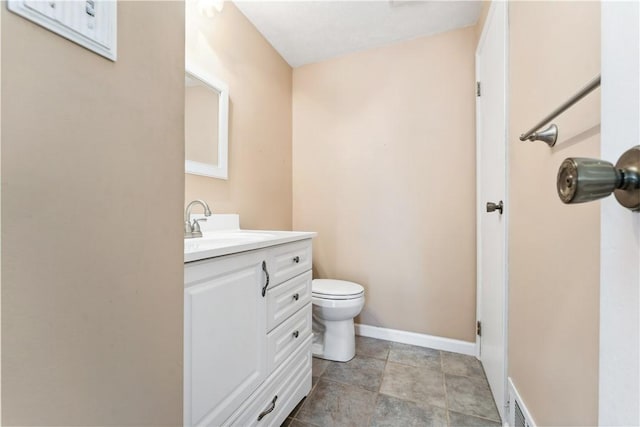 half bath with visible vents, baseboards, vanity, and toilet