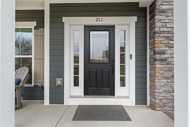 view of exterior entry with covered porch and stone siding