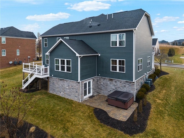 rear view of property featuring a hot tub, a lawn, stairway, a patio area, and central AC