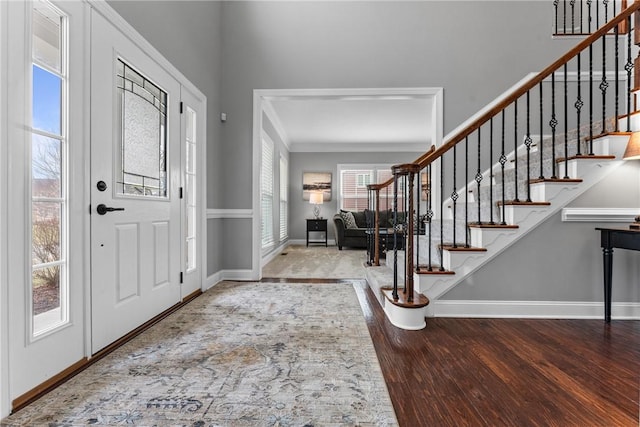 foyer featuring stairs, ornamental molding, baseboards, and wood finished floors