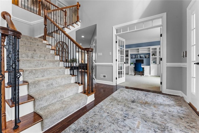 foyer featuring french doors, stairway, a towering ceiling, wood finished floors, and baseboards