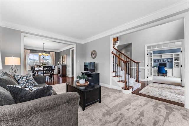 carpeted living area featuring baseboards, stairs, crown molding, french doors, and a notable chandelier