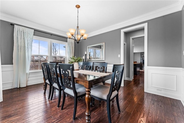 dining area featuring ornamental molding, wainscoting, a notable chandelier, and hardwood / wood-style flooring