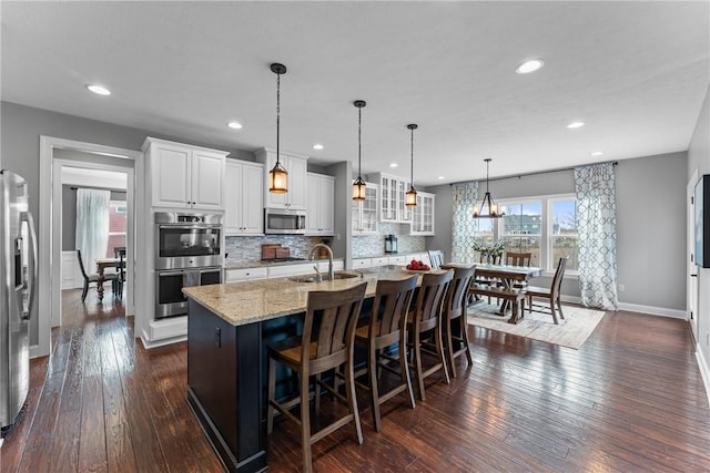 kitchen with stainless steel appliances, backsplash, glass insert cabinets, white cabinets, and a sink