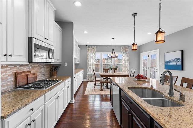 kitchen featuring a sink, white cabinets, appliances with stainless steel finishes, backsplash, and dark wood-style floors