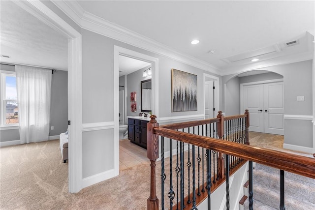 hallway with light carpet, crown molding, visible vents, and an upstairs landing