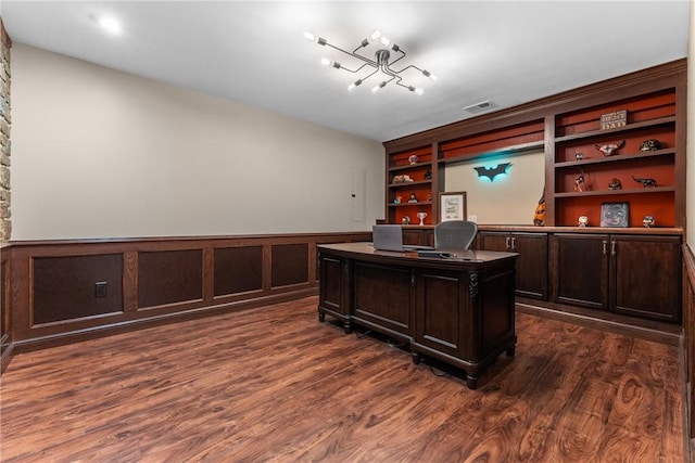 office area featuring a wainscoted wall, dark wood-style flooring, visible vents, and built in features