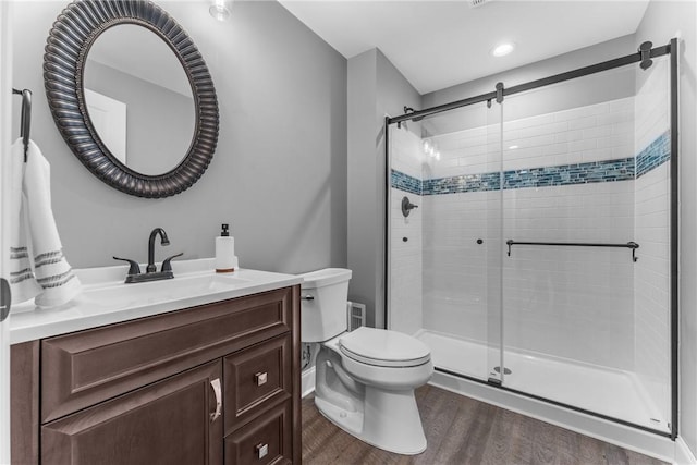 bathroom featuring vanity, a stall shower, wood finished floors, and toilet