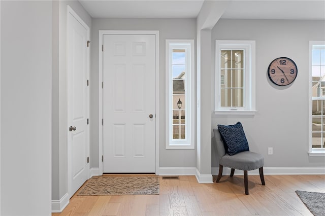 foyer entrance with light wood-style floors and baseboards