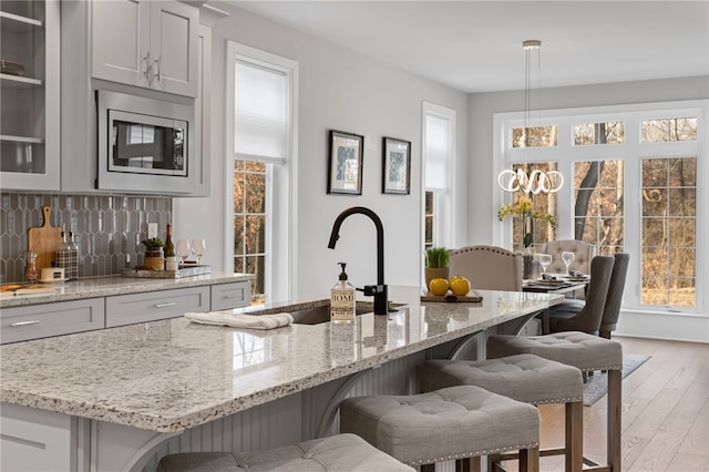 kitchen with decorative backsplash, stainless steel microwave, a kitchen breakfast bar, and a sink