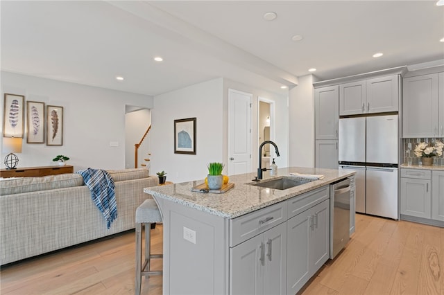 kitchen featuring a sink, stainless steel appliances, gray cabinets, and light wood-style flooring